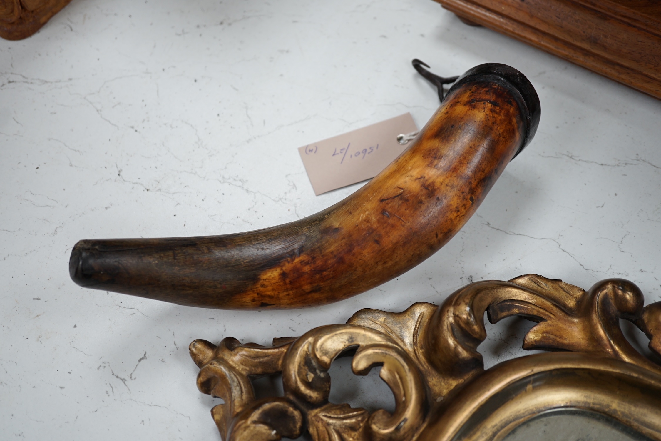 A 19th century giltwood mirror, a powder horn and a pair of tribal carved wood figures, mirror 55cm long. Condition - fair to good